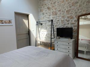 a bedroom with a bed and a television on a dresser at Le Mas du Pigeonnier in Réauville
