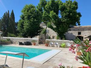 a swimming pool in a yard with a stone wall at Le Mas du Pigeonnier in Réauville