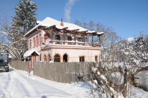 a house covered in snow in front of a fence at vila zia in Corbeni