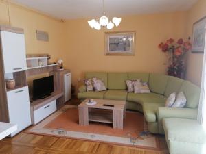 a living room with a green couch and a table at Apartments Čubranić in Baška