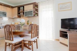 a kitchen with a wooden table and chairs and a television at Apartman Tradicija in Kaštela +42 photos