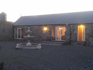 una casa de piedra con una fuente frente a ella en The Stables en Castle Douglas