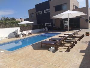 een zwembad met ligstoelen en een parasol bij Casa Can Miras in Comarruga