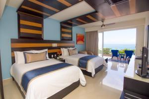 two beds in a room with a view of the ocean at Secrets Huatulco Resort & Spa in Santa Cruz Huatulco