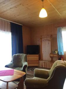 a living room with two chairs and a table at Domki Baryła z Sauna i Basenem in Sulęczyno