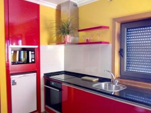 a red kitchen with a sink and a window at Casa da Oliveira in Milhão