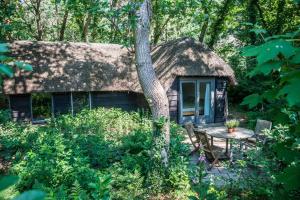 a cabin in the woods with a table and a thatch roof at Aa Casia vakantiehuis in Zeegse
