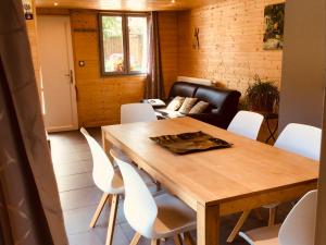 a dining room with a wooden table and white chairs at Le duplex De La Ferme Du Tertre in Villers-au-Tertre
