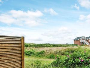 a fence in a field with a house in the background at 4 person holiday home in R m in Rømø Kirkeby