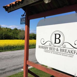 un cartel para un bed and breakfast de granja junto a una carretera en Borrby B&B, en Borrby