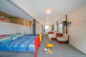 a bedroom with a bed and a couch and a tv at Coastal Hill Retreat - Tairua Holiday Home in Tairua