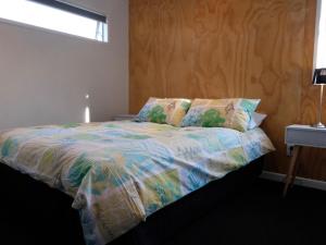 Una cama con un edredón colorido en un dormitorio. en Stargazer - Ohakune Holiday Home, en Ohakune