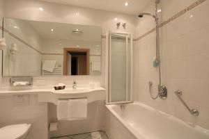 a bathroom with a tub and a sink and a toilet at Hotel-Restaurant Esbach Hof in Kitzingen