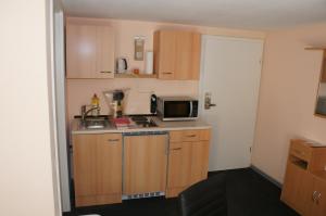 a small kitchen with wooden cabinets and a microwave at Ferien-/Monteurwohnung Olbrich in Hilchenbach