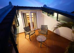 two chairs and a table on a balcony at night at Heeren Straits Hotel in Malacca