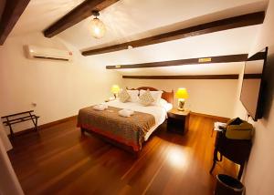 a bedroom with a bed and a lamp on a wooden floor at Heeren Straits Hotel in Malacca