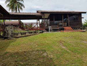 een huis met een grasveld ervoor bij Kampong Style Homestay Pengkalan Balak - Sea View in Pengkalan Balak