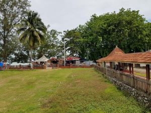 ペンカラン・バラックにあるKampong Style Homestay Pengkalan Balak - Sea Viewの塀と建物とヤシの木がある庭