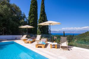 una piscina con tumbonas y sombrillas junto a una piscina en Odyssey villas, en Kassiopi