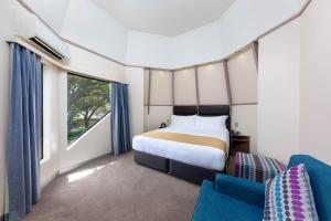 a bedroom with a bed and a blue chair at Holiday Inn Auckland Airport by IHG in Auckland