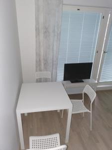 a white desk with a computer and chairs in a room at Vaunukatu in Turku