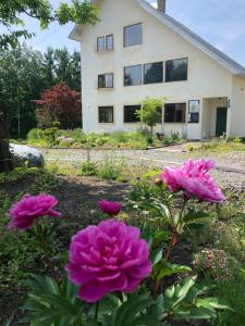 a house with pink flowers in front of it at Auberge Ninguruforet in Biei