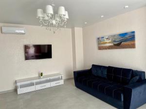 uma sala de estar com um sofá azul e uma televisão em Золотой Бугаз Грибовка em Gribovka