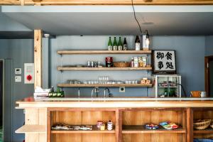 eine Küche mit einer Theke mit einer Spüle und Regalen in der Unterkunft Arashima Hostel in Ōno