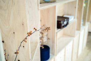 a plant in a blue vase on a wooden wall at Arashima Hostel in Ōno