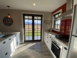 a kitchen with white cabinets and a door with a view at Pedalfish Cottages - Galaxy Views in Twizel