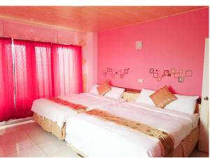 two beds in a room with pink walls and windows at 別野山莊民宿 in Baisha