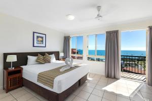 a bedroom with a bed with a view of the ocean at Martinique Whitsunday Resort in Airlie Beach