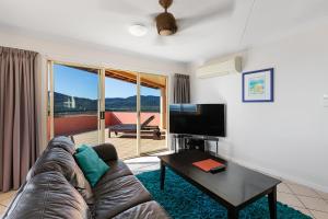 a living room filled with furniture and a tv at Martinique Whitsunday Resort in Airlie Beach