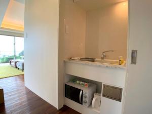 eine Küche mit Spüle und Mikrowelle in der Unterkunft KEN KEN VILLA YUUMODORO in Motobu
