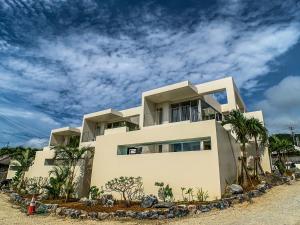 ein weißes Haus mit Palmen davor in der Unterkunft KEN KEN VILLA YUUMODORO in Motobu