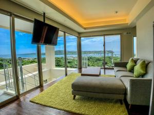 a living room with a couch and a tv and windows at KEN KEN VILLA YUUMODORO in Motobu