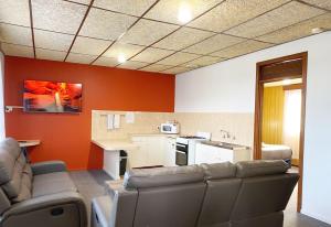 a living room with couches and a kitchen with orange walls at Limestone Coast Tourist Park in Mount Gambier