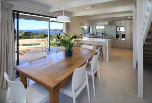 uma cozinha e sala de jantar com uma mesa de madeira e cadeiras em Noll View em Oneroa