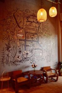 a wall with a mural with a table and chairs at Bangpho Story in Bangkok