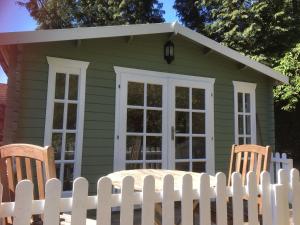 法納姆的住宿－Woodland Cabin With private Wood-Fired Hot-Tub，绿色房屋,设有白色围栏