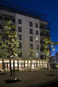 un edificio alto con alberi di fronte di Domitys Le Pont des Lumières a Lione