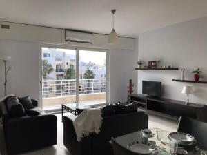 a living room with couches and a television and a balcony at Ocean Pearl Apartment no4 in St. Paul's Bay