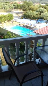 a table and a chair on a balcony with a swimming pool at Armonia Apartment in Potos