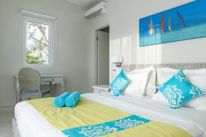 Schlafzimmer mit einem Bett mit blauen und weißen Kissen in der Unterkunft Voile Bleue Boutique Hotel in Trou aux Biches