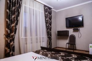 a bedroom with a bed and a tv and a window at VIP Mini Hotel in Semey
