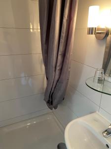 ein Bad mit einem Duschvorhang und einem Waschbecken in der Unterkunft Hotel Restaurant Rössle in Calw