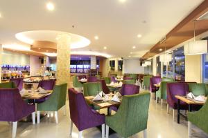 un restaurante con mesas y sillas de color púrpura y verde en Swiss-Belinn Balikpapan, en Balikpapan