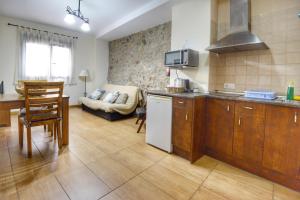 a kitchen and living room with a couch in the background at Apartamentos Rurales La Vera in Jarandilla de la Vera