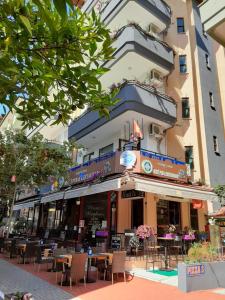 a building with tables and chairs in front of it at Musti Apart Hotel in Alanya