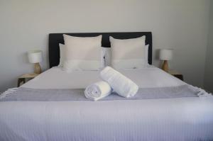 Una cama blanca con dos toallas enrolladas. en Caves Coastal Bar & Bungalows en Caves Beach